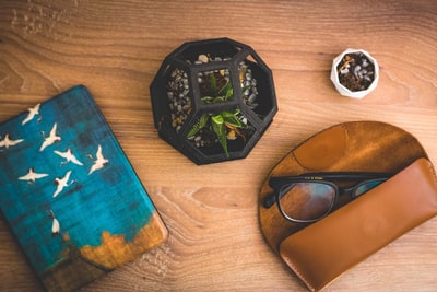 黑色圆玻璃烟灰缸旁边棕色皮革两褶的钱包
